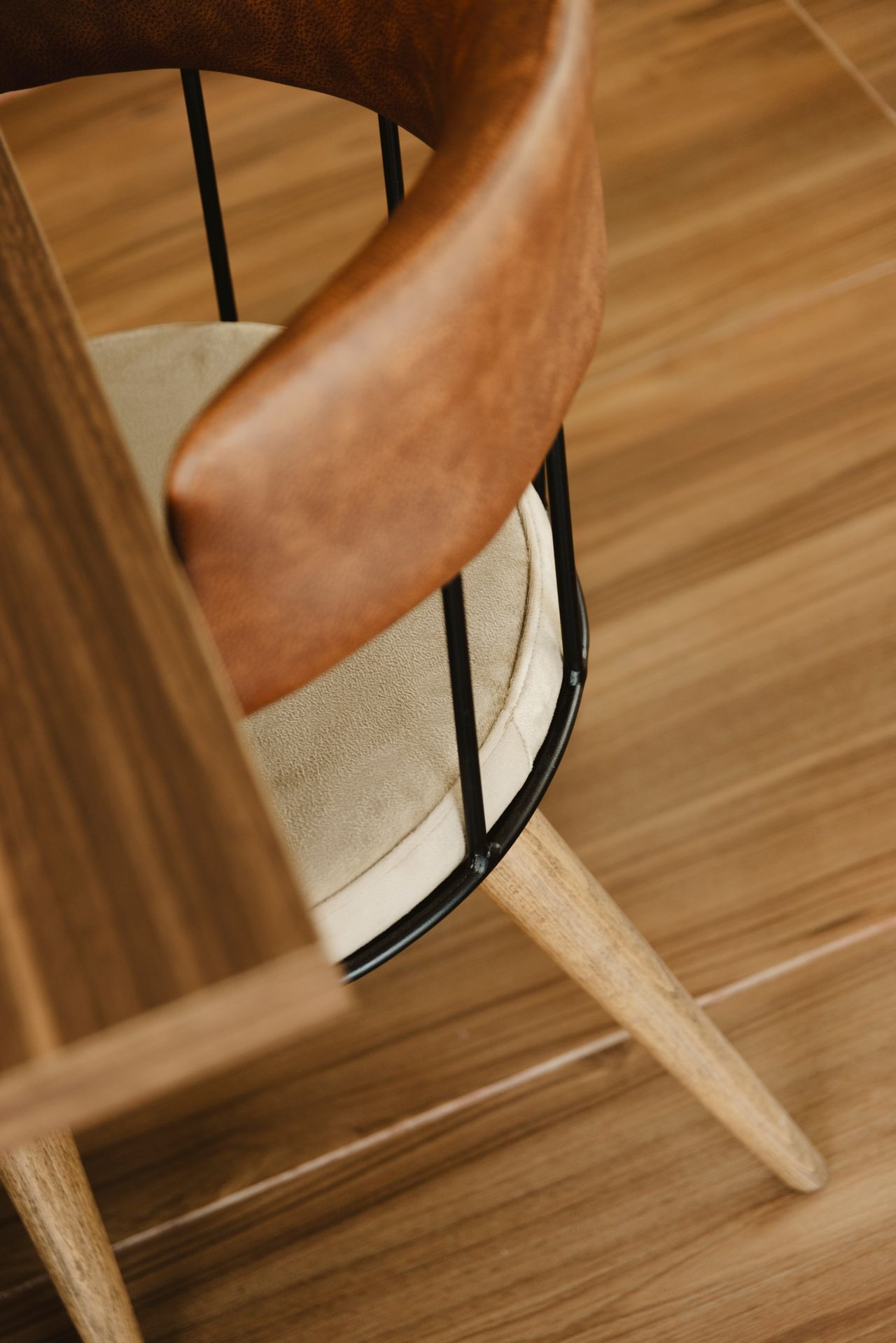 Close-up of a curved leather armrest on an armchair at a wooden table