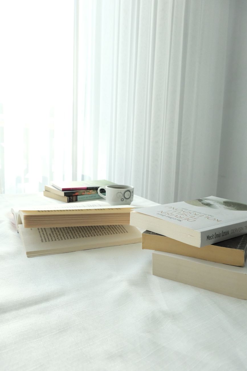 A serene setup of books and a coffee cup by a sunlit window, perfect for reading.