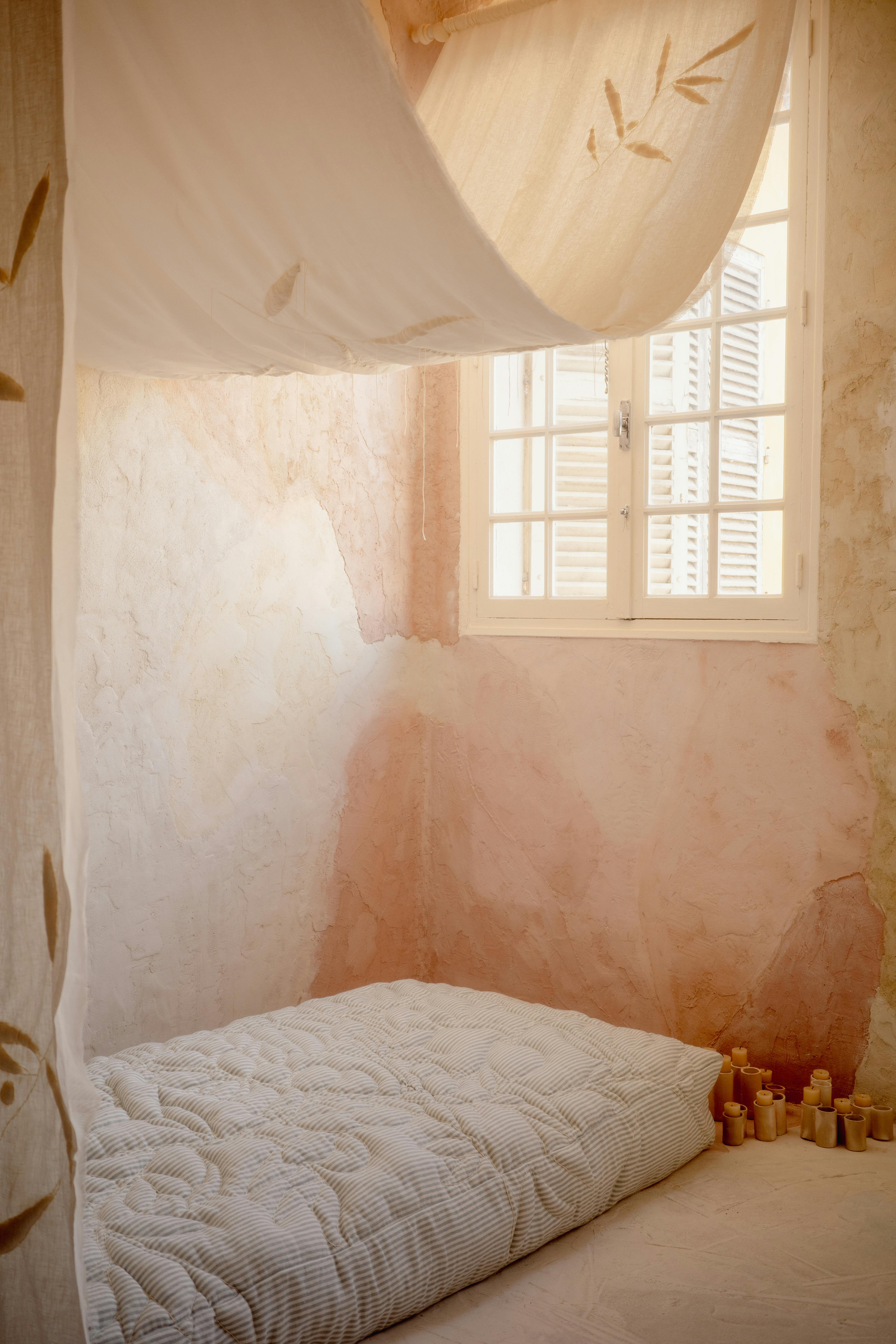 Warm and peaceful minimalist bedroom with soft natural lighting and gentle pink tones.