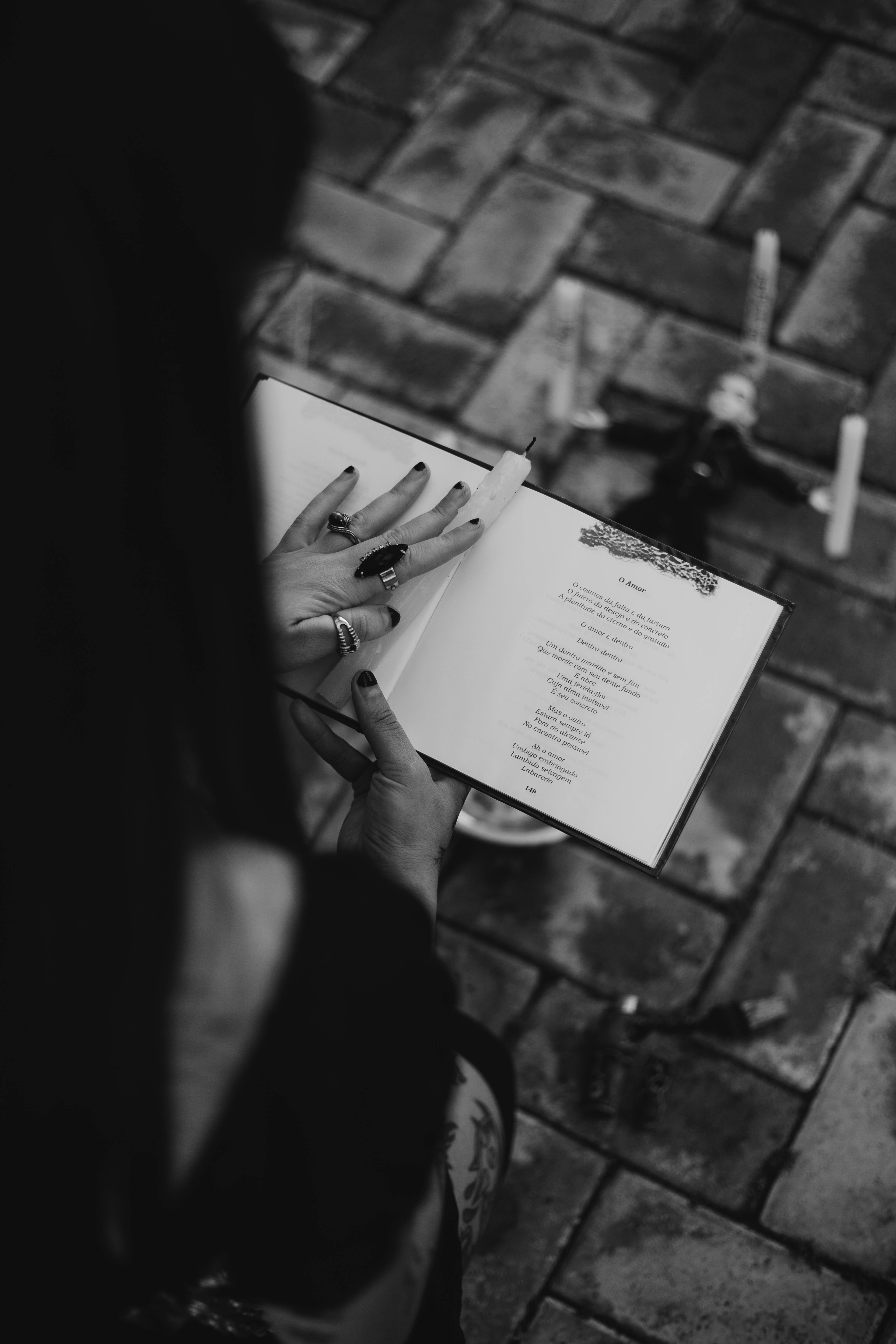 Zadarmo Čiernobiela fotografia zachytávajúca mystický rituál s otvorenou knihou a sviečkami na dlažobných kockách. Fotka z fotobanky