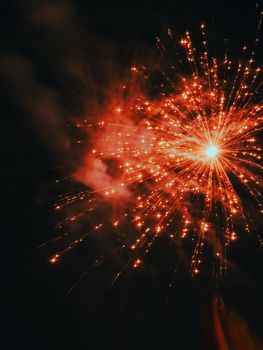 Vibrant orange fireworks burst against a dark night sky, creating a stunning display.