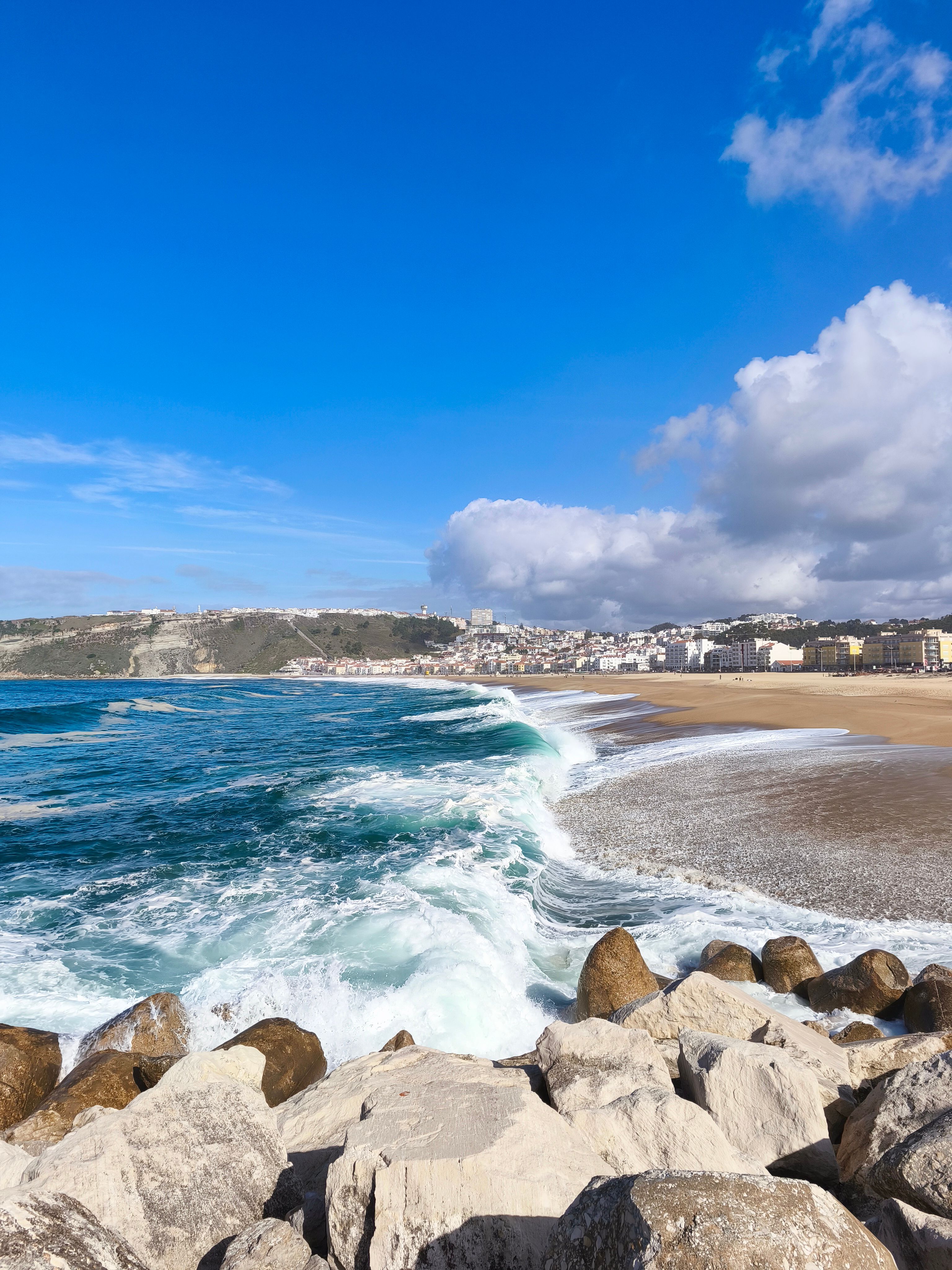 Breathtaking view of Nazaré beach with waves crashing against rocks, Portugal