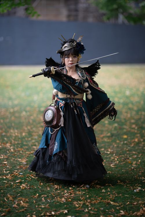 Free Female cosplayer in ornate costume posing with sword outdoors on a fall day. Stock Photo
