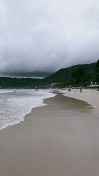 A tranquil beach scene with cloudy sky and lush hills, perfect for relaxation and nature lovers.