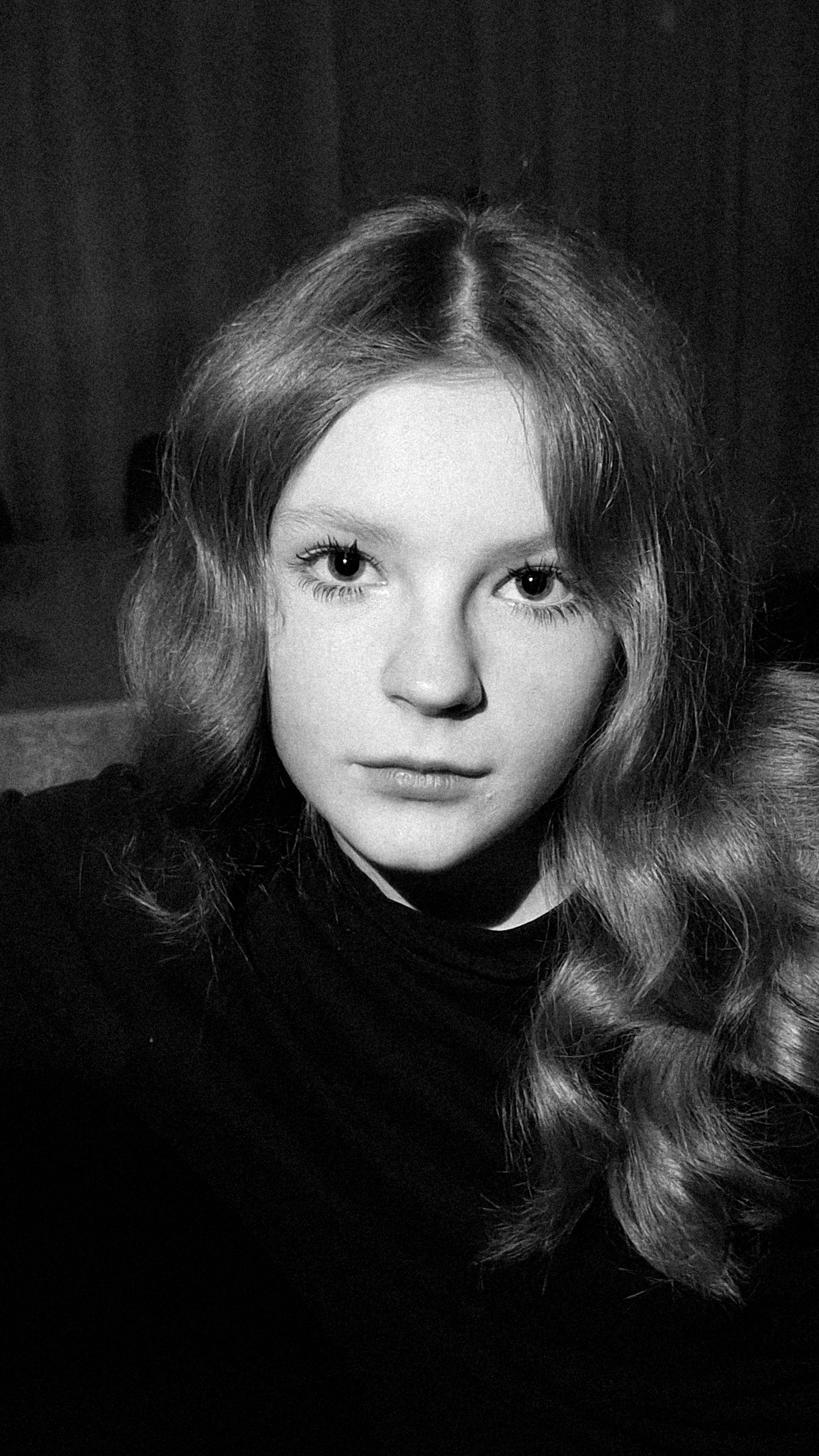 Close-up portrait of a young woman in black and white, evoking a classic and moody atmosphere.