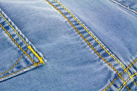 Detailed close-up of blue denim fabric showcasing yellow stitching and texture.