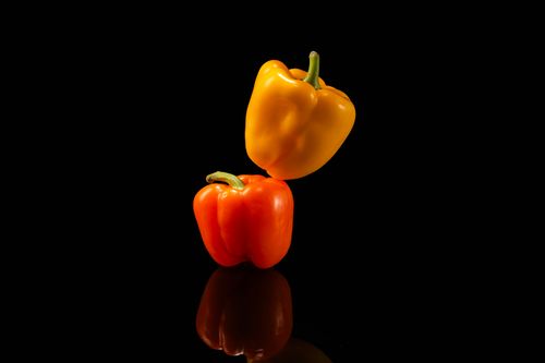 Free Colorful red and yellow bell peppers artfully arranged against a black backdrop. Stock Photo