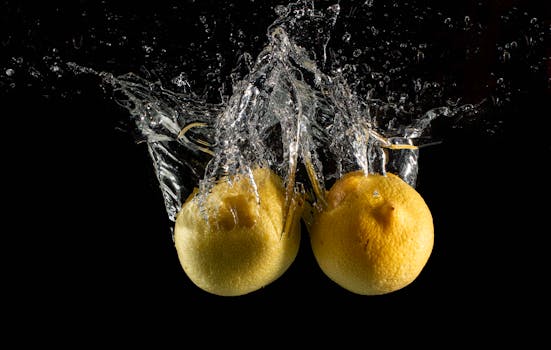 Two lemons captured mid-splash in water against a black background.