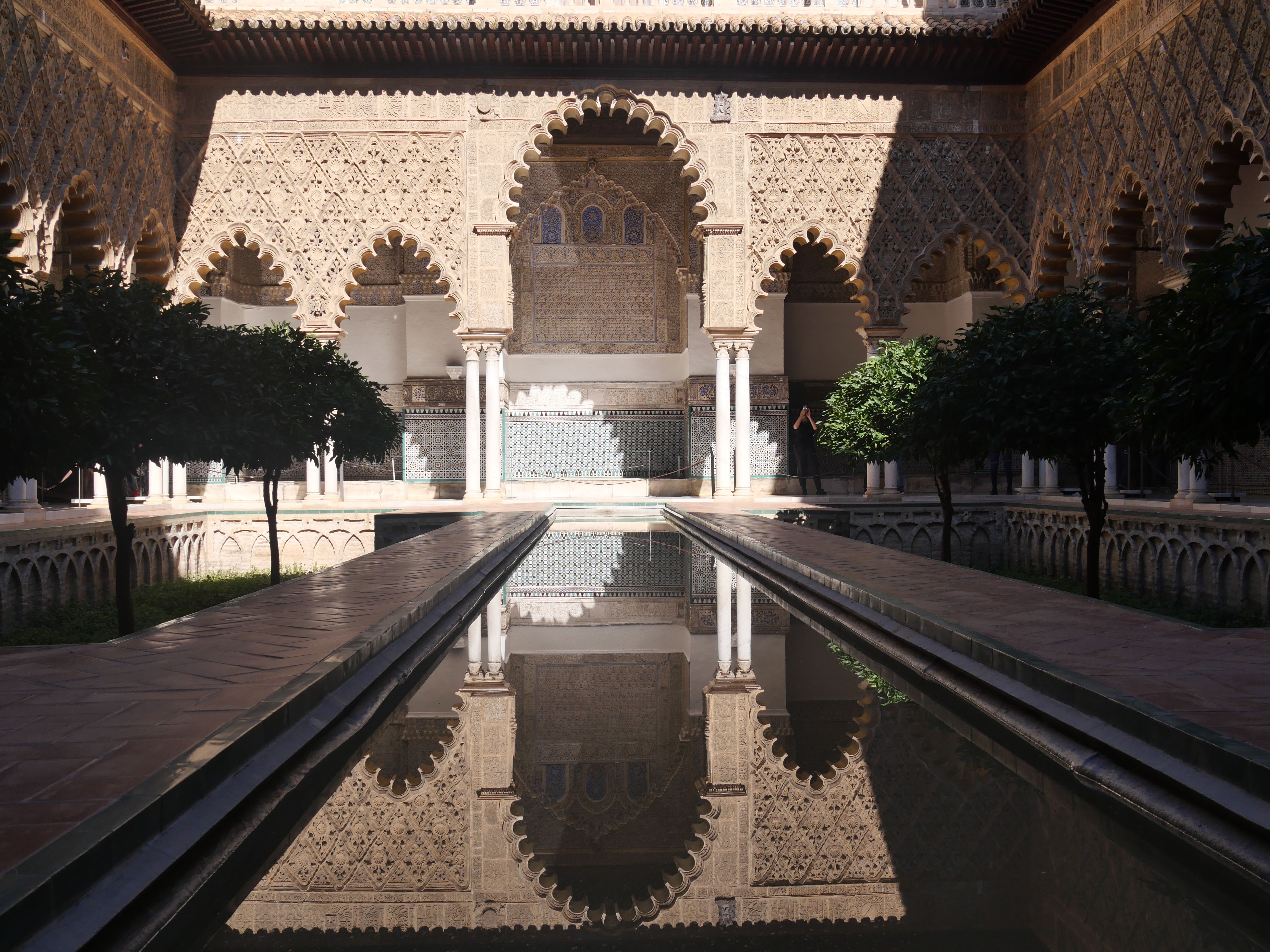 Explore the intricate Moorish architecture with reflections at the Alcazar in Seville, Spain.