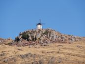 Captivating view of an iconic Spanish windmill on a rocky hill under a clear blue sky.