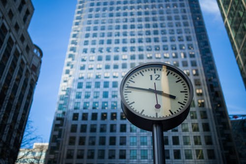 Black and Gray Round Analog Watch at 3:47 Across High Rise Building