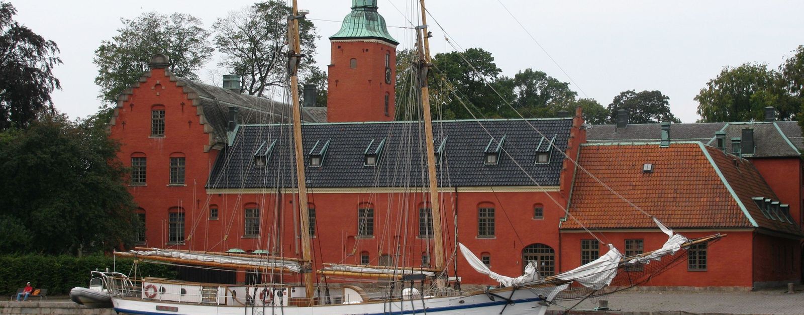 A classic sailing ship docked by a red brick building, capturing Sweden's maritime heritage.