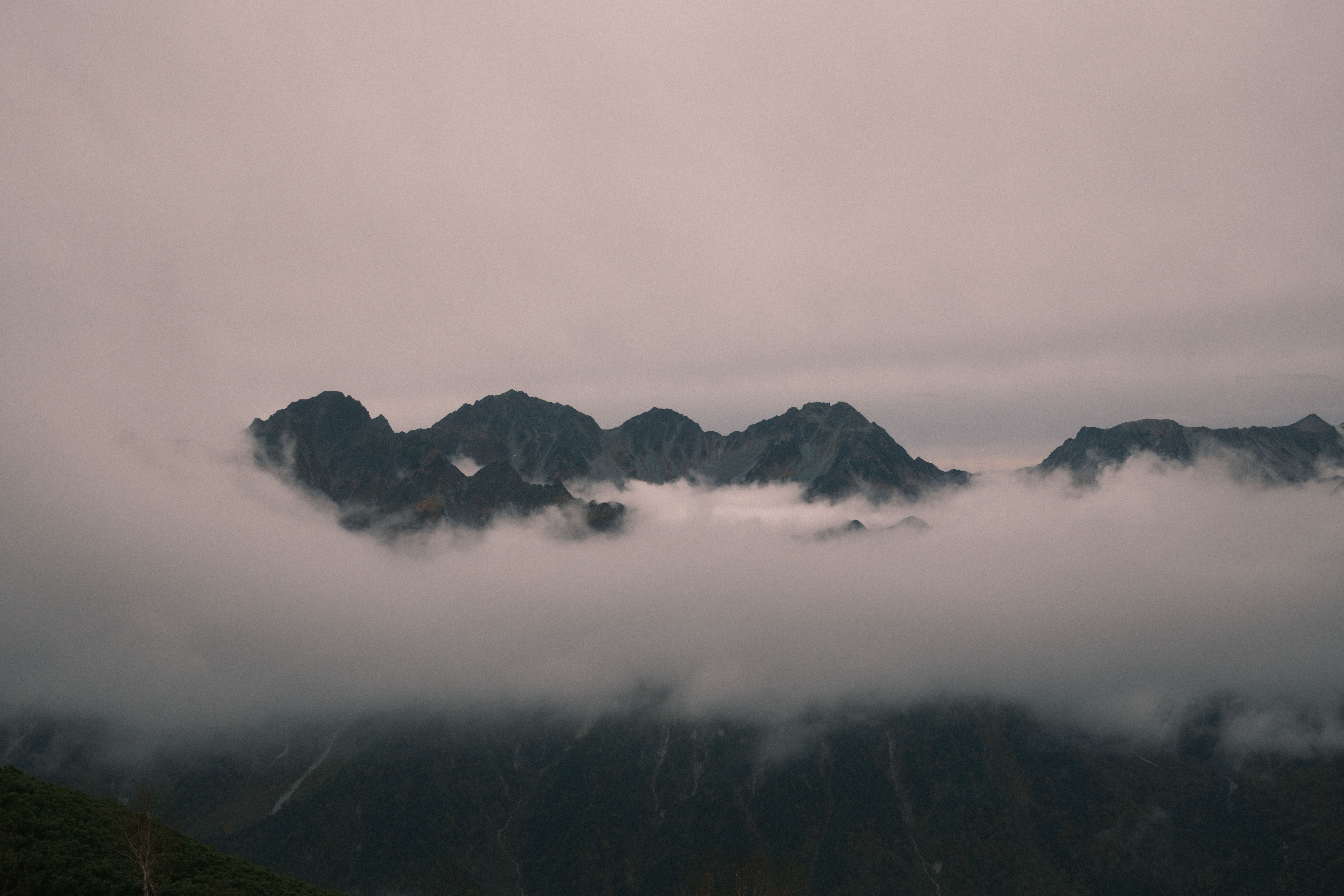 Dramatic misty view of mountain peaks in Azumino, Nagano, Japan, at twilight.