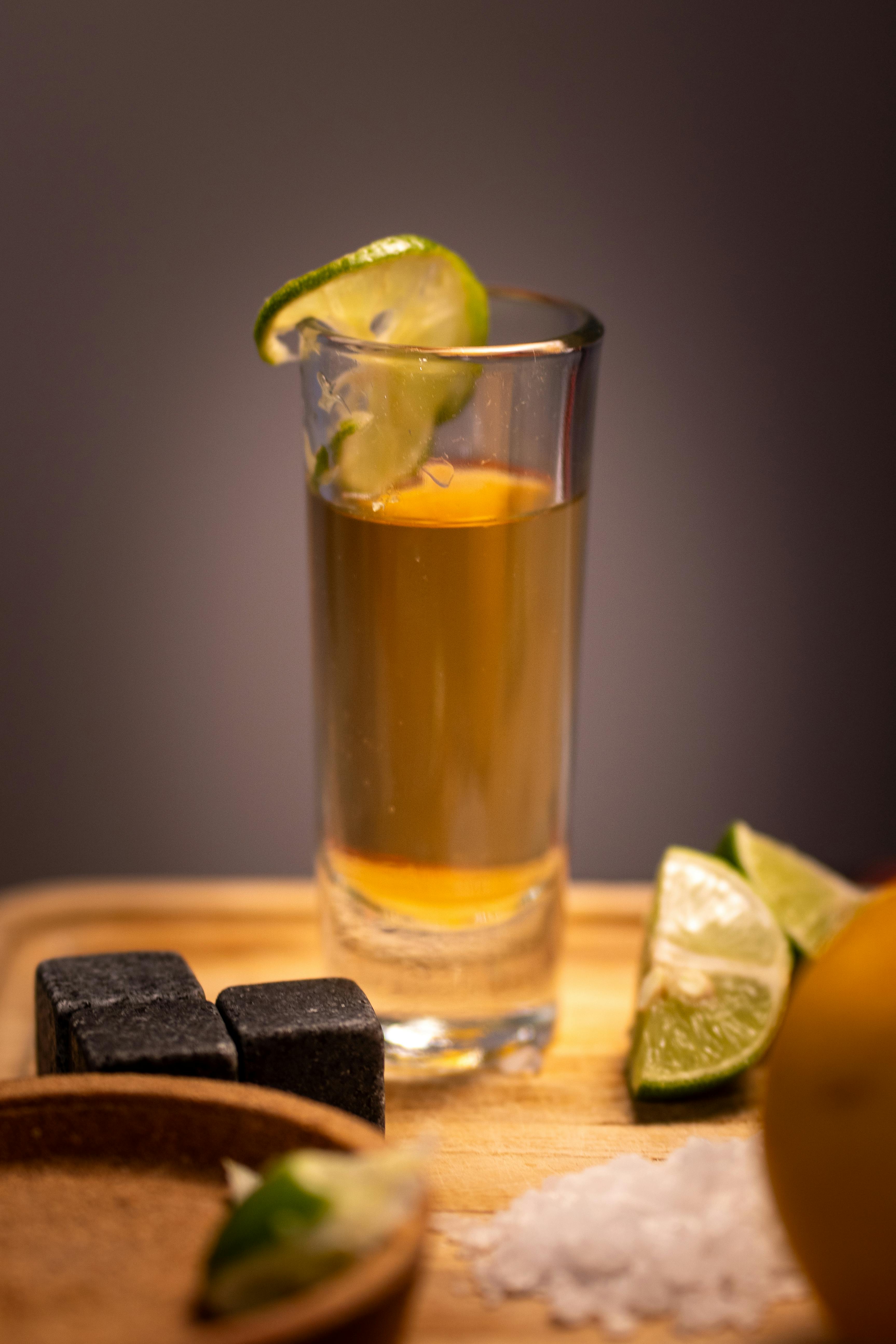 A classic tequila shot with lime and salt, captured in a warm setting. Perfect for a Mexican-themed gathering.