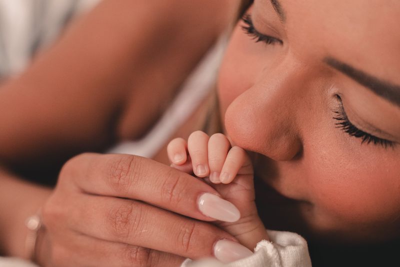 Madre sosteniendo la mano de su bebé recién nacido