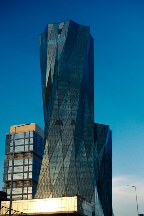 Free Architectural shot of a modern glass skyscraper under a clear blue sky. Stock Photo