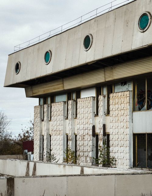 Free A striking image of a modernist-style abandoned building with round windows and a weathered facade. Stock Photo