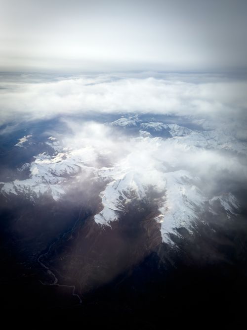 Free Breathtaking aerial photo of mist-covered snowy mountain peaks during winter. Stock Photo
