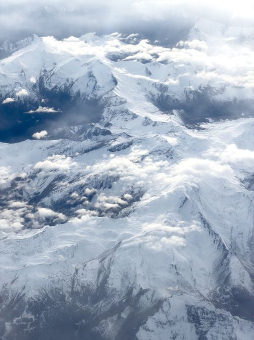 Free Stunning aerial view of snow-laden Alps with clouds drifting across the peaks. Stock Photo