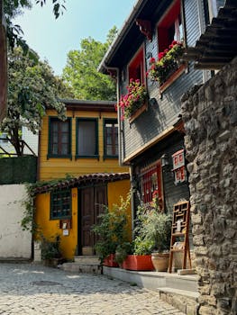 Colorful historic houses in a charming cobblestone alley, showcasing vibrant flowers and classic architecture.