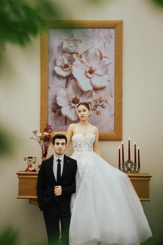Bride and groom pose elegantly indoors against a floral backdrop in Antalya.