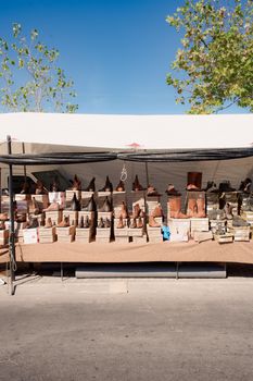Market stall displaying a variety of leather boots outside under a tent on a sunny day.