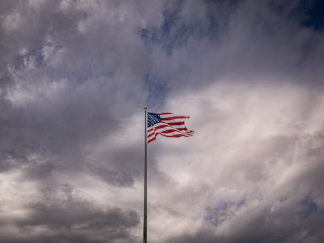 A vibrant American flag waving against a cloudy, dramatic sky.