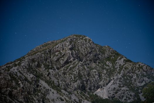 Majestic rocky mountain peak against a clear, starry night sky. Ideal for nature and travel themes.