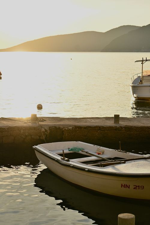 Free Captivating sunset scene of boats by the sea in Montenegro with mountains in the background. Stock Photo