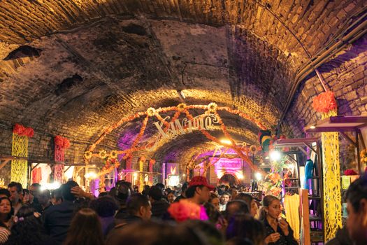 Lively Dia de los Muertos celebration inside a Guanajuato tunnel, featuring colorful decorations and a festive crowd.