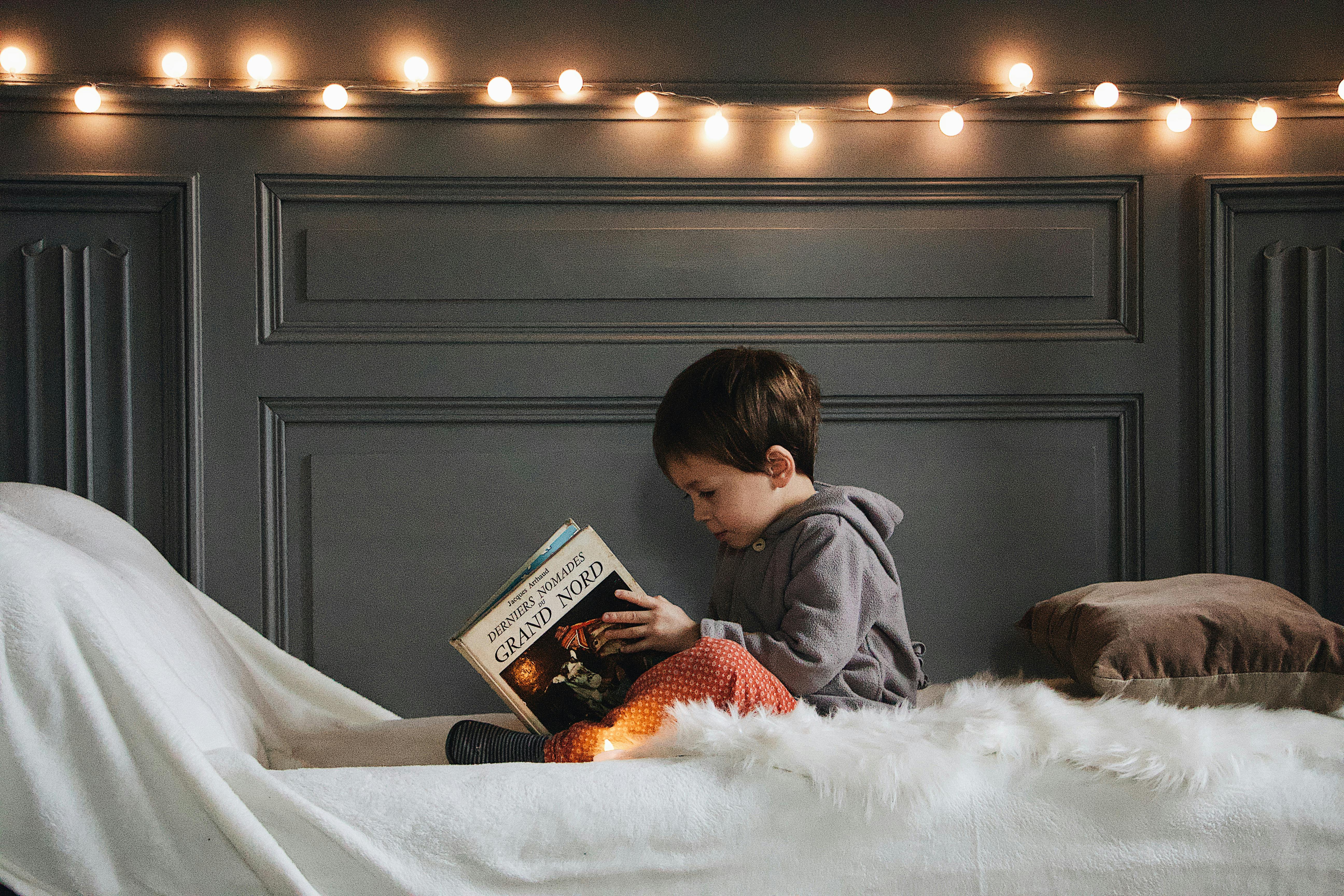 boy in gray jacket reading book