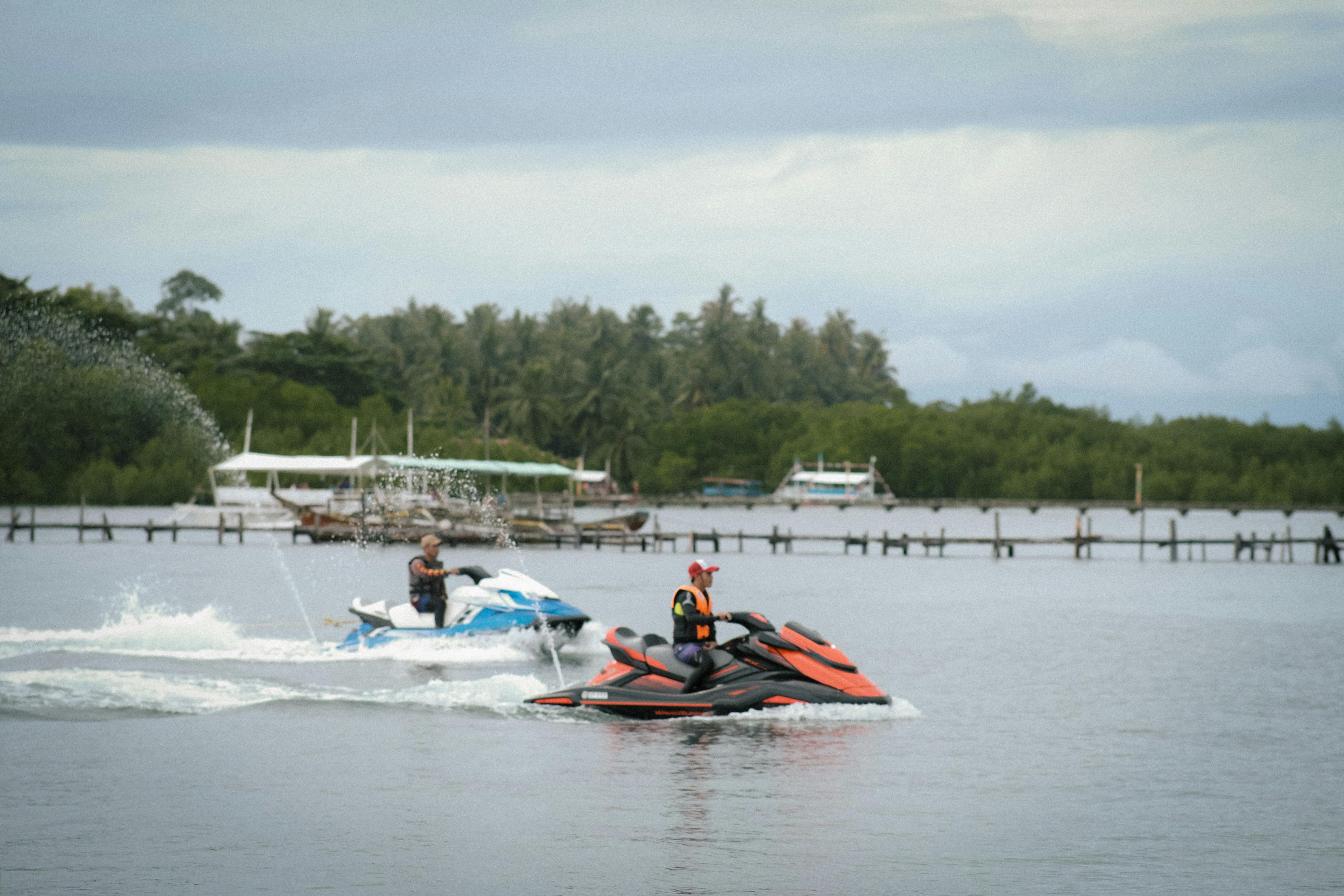Two people enjoy a jet ski ride on a tropical lake under cloudy skies.