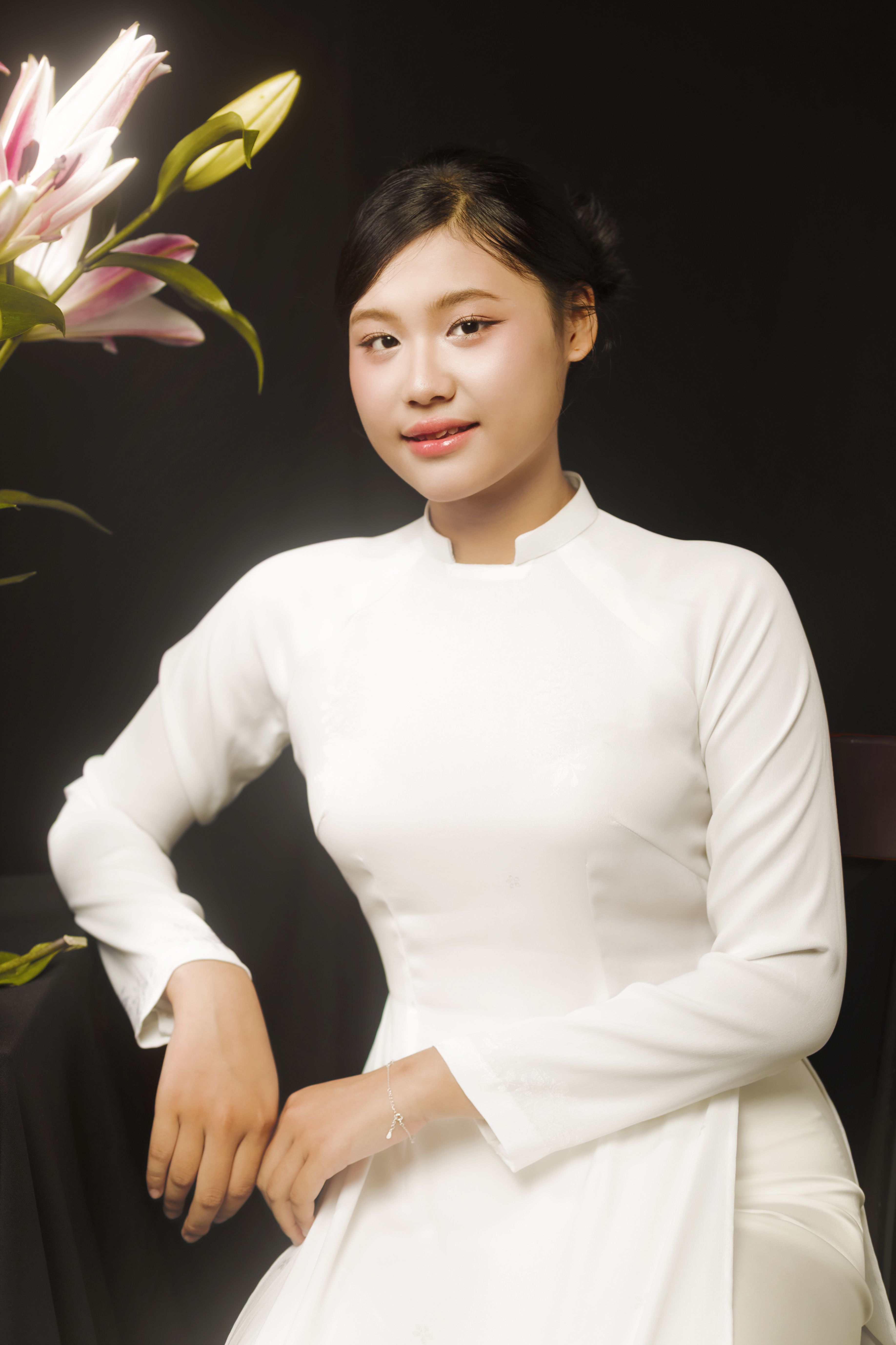 Elegant portrait of a woman in a traditional white dress with lilies against a dark background.