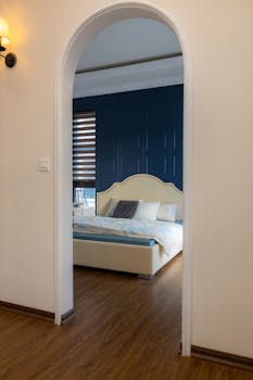 Cozy bedroom with blue accent wall and modern archway for a stylish ambiance.