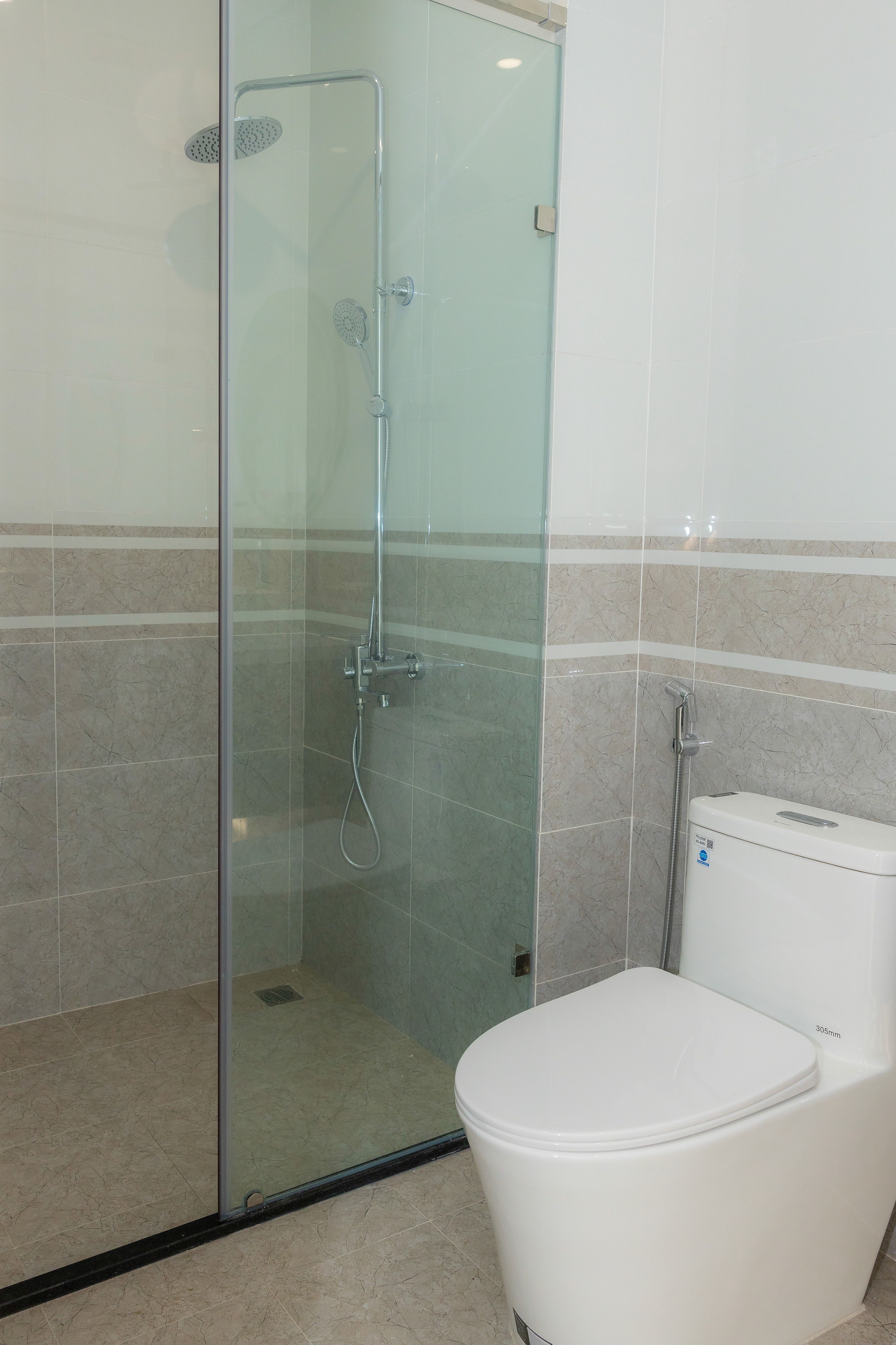 A clean and spacious modern bathroom featuring a glass shower enclosure and toilet.