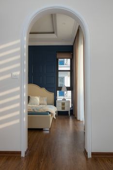 Discover a chic bedroom with natural light and cozy decor framed by an elegant archway.