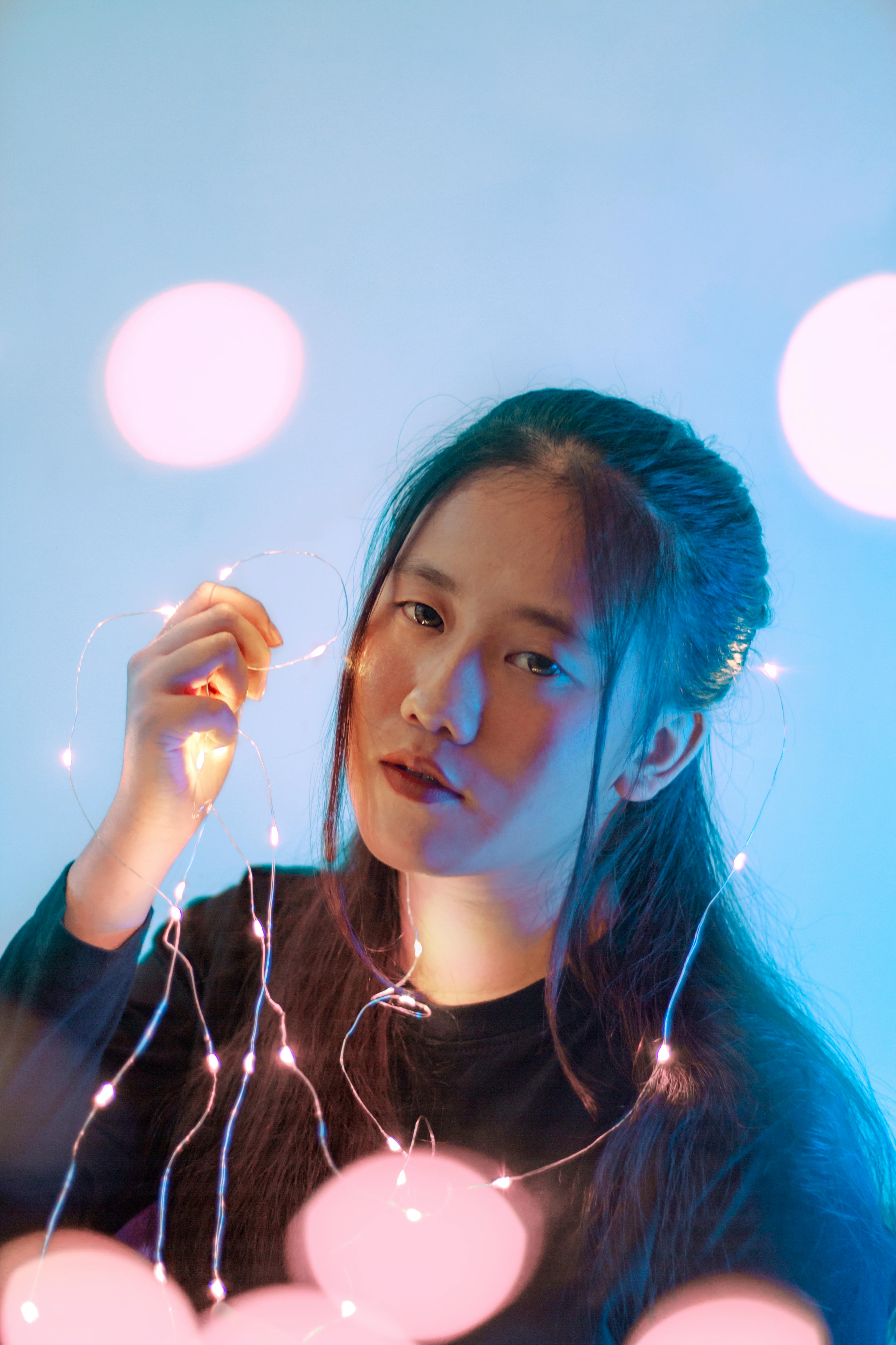 一位手持仙女灯的女人，表情安详地站在充满活力的蓝色背景前