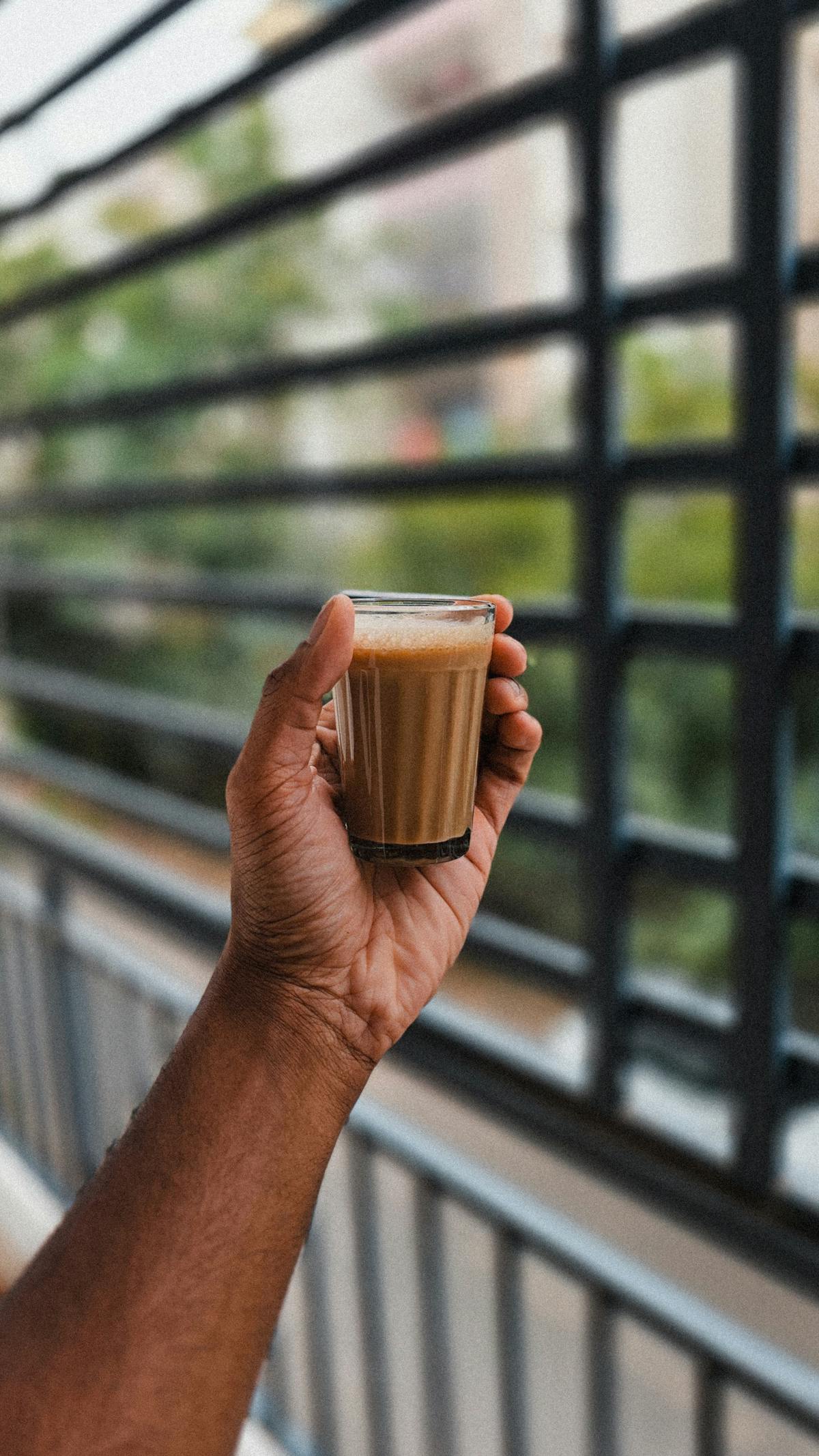 Hand holding a small coffee glass near a window
