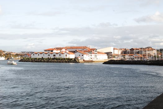 Charming coastal town with white buildings and red roofs by the water on a sunny day.