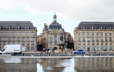 Vue imprenable sur la place de la Bourse à Bordeaux, avec son reflet sur le trottoir mouillé.