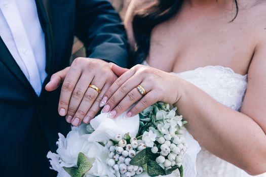 Close-up of couple's hands with wedding rings over a bouquet in Auburn, NSW.