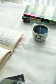 A peaceful moment with an open book, a cup of coffee, and a stack of books on a table.