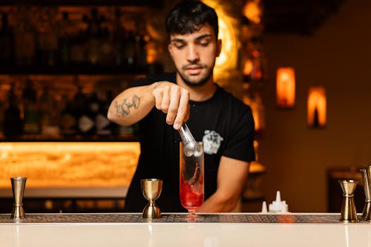 Young bartender expertly crafting a cocktail in a trendy, dimly-lit bar setting.