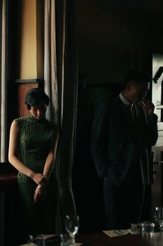 A vintage-style portrait of a stylish couple in low light indoors.