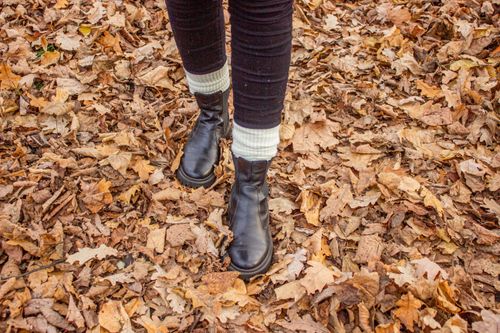 Free Close-up of a woman's boots walking through fallen autumn leaves, showcasing fall fashion and seasonal colors. Stock Photo