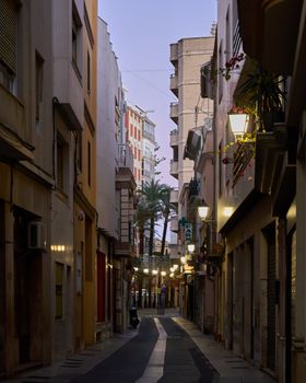 Cozy narrow street in urban setting at twilight with warm lights and architectural details.