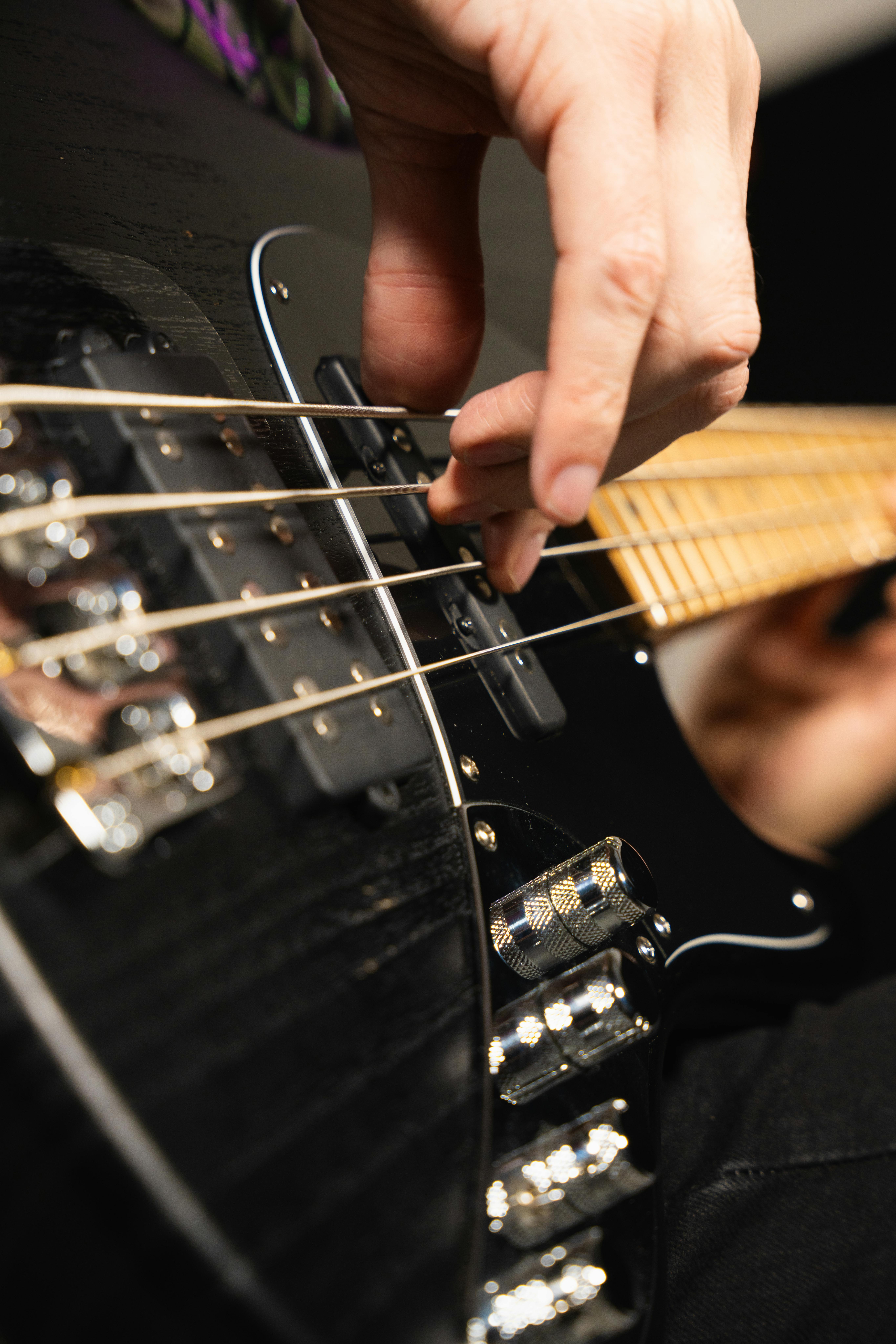 Detailed shot of a musician's hand playing an electric bass guitar in a studio setting.