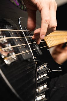 Detailed shot of a musician's hand playing an electric bass guitar in a studio setting.