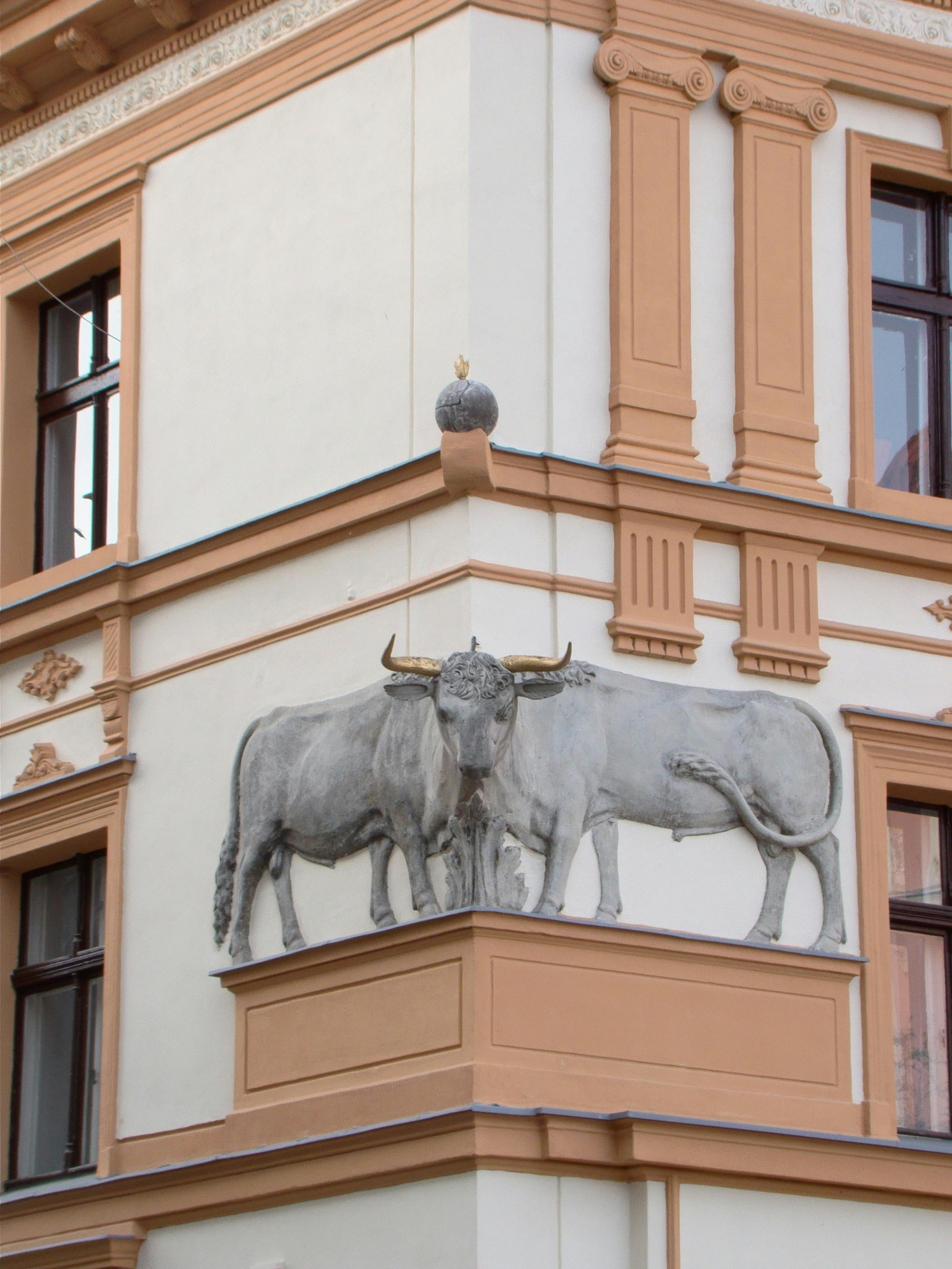Free Sculptural bulls adorn a historic building corner with classical architectural details. Stock Photo