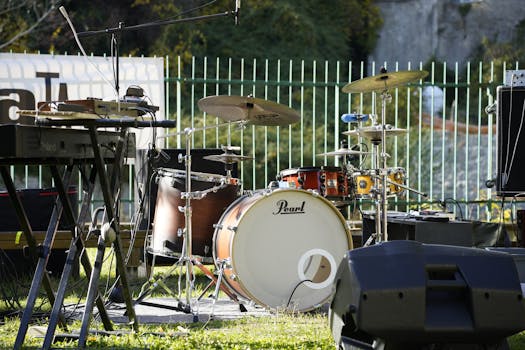 An outdoor music stage setup featuring a drum set and keyboard, ready for a live performance.